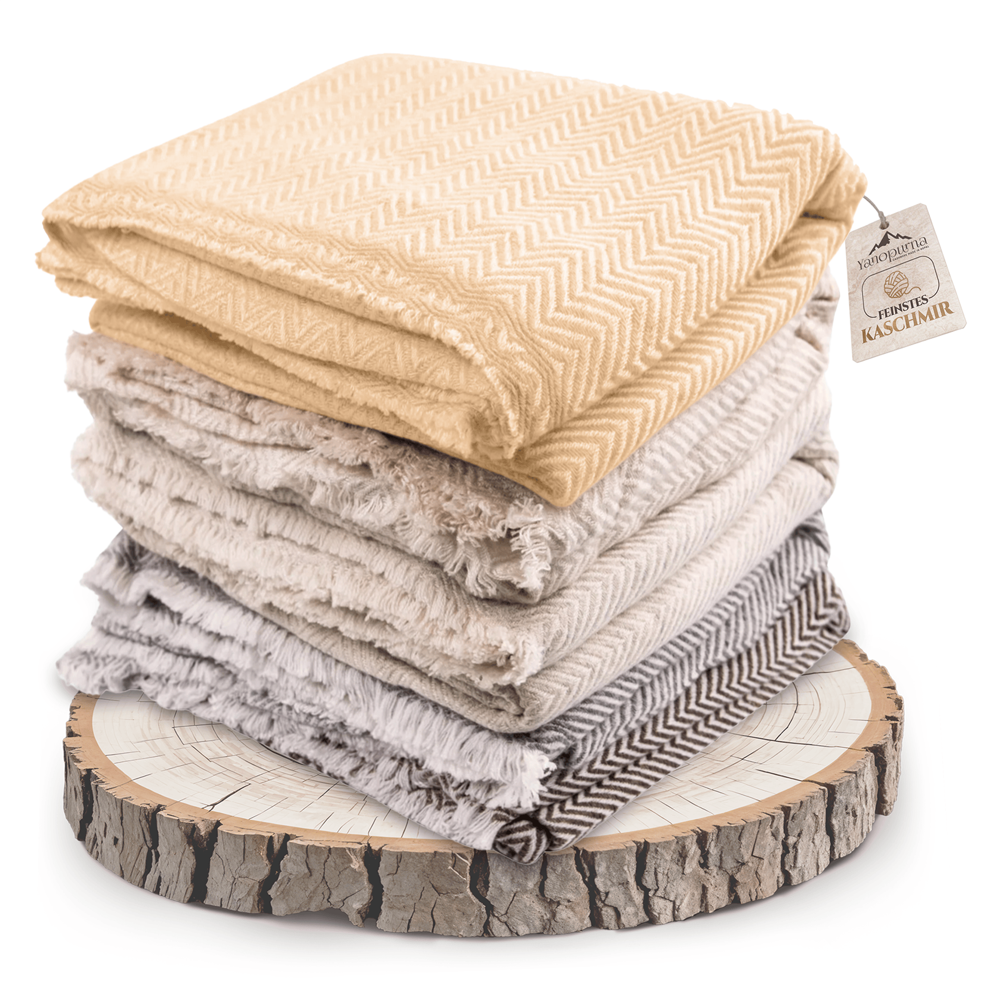 Auf dem Bild ist ein Stapel mehrerer gefalteter Kaschmirdecken in verschiedenen Beige- und Grautönen zu sehen. Die obere Decke ist goldbeige und mit einem großen Fischgrätenmuster versehen. Alle Decken liegen auf einer runden Holzplatte mit Rindenrand. Einige Decken haben ausgefranste Kanten. Rechts am Stapel hängt ein Etikett mit der Aufschrift „Feinstes Kaschmir“.